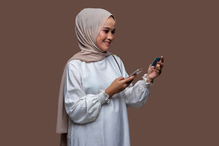 Young women in hijab holding credit cards and cellphones smile looking at the cameraの写真素材
