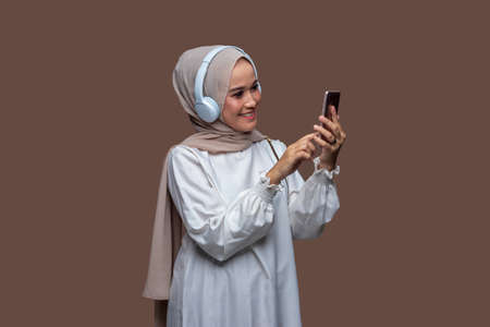 Young hijab woman using wireless headphones enjoy listening musicの写真素材
