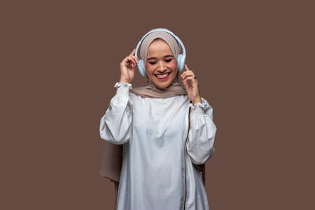 Happy indonesian woman using wireless headphones enjoy music while dancing and rockingの写真素材