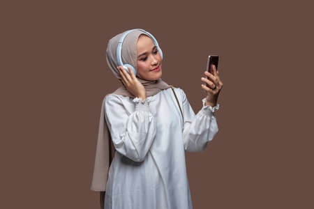 Young hijab woman using wireless headphones enjoy listening musicの写真素材