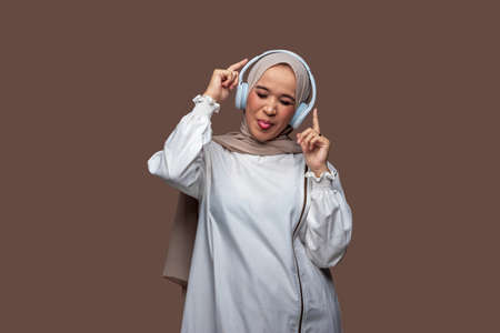 Happy asian woman using wireless headphones enjoy music while dancing and rockingの写真素材