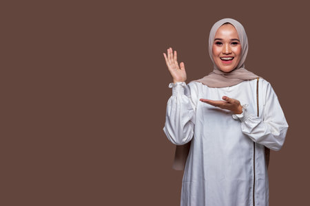 Beautiful hijab woman showing present gesture hand isolated on plain backgroundの写真素材