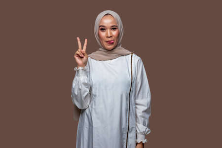 Beautiful hijab women with peaceful hand gestures isolated on plain backgroundの写真素材