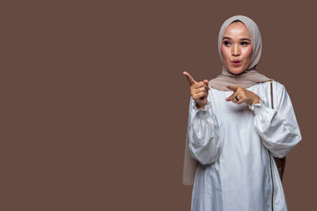 Beautiful indonesian woman wearing hijab is pointing to the front sideの写真素材