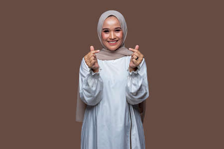 Young beautiful woman in hijab with saranghae korean hand gesture isolated on plain backgroundの写真素材