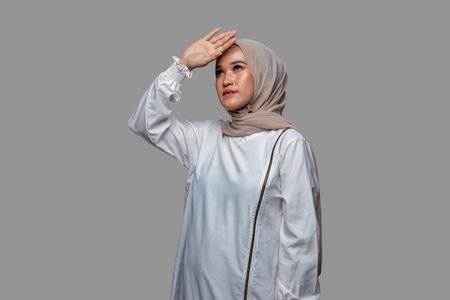 Beautiful woman is looking up and posing raises one hand isolated on plain backgroundの写真素材
