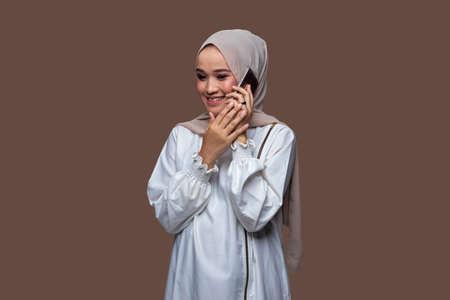 Beautiful woman in a hijab whispering on her cellphone with smile expression on her faceの写真素材