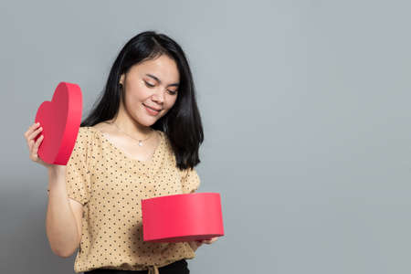 Beautiful woman holding like a pizza box and pointing to the rightの写真素材