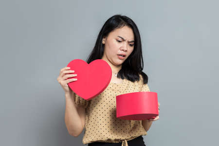 Beautiful woman holding like a pizza box and pointing to the rightの写真素材