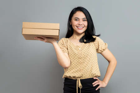 Beautiful woman holding like a pizza box and pointing to the rightの写真素材