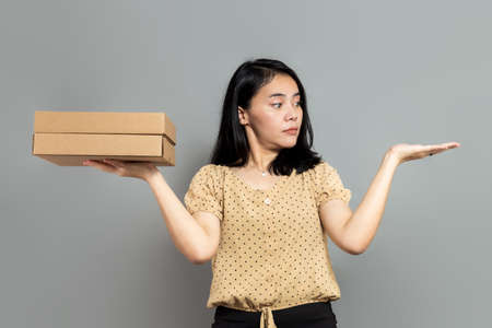 Beautiful woman holding like a pizza box and pointing to the rightの写真素材
