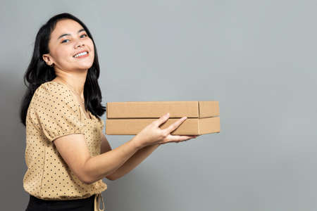 Beautiful woman holding like a pizza box and pointing to the rightの写真素材