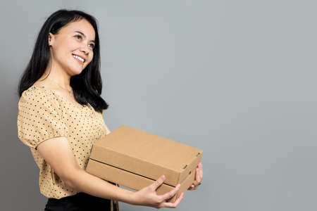 Beautiful woman holding like a pizza box and pointing to the rightの写真素材