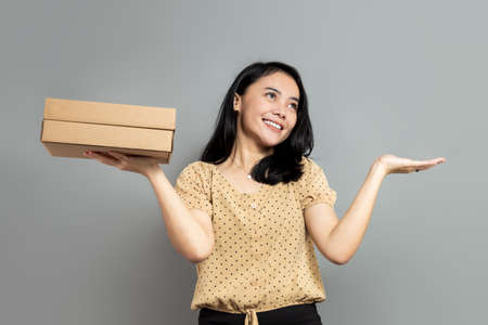 Beautiful woman holding like a pizza box and pointing up with index fingerの写真素材