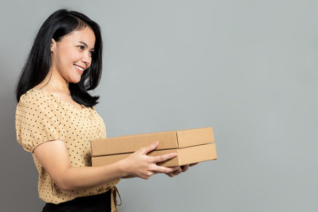 Beautiful woman holding like a pizza box and pointing up with index fingerの写真素材
