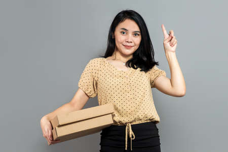 Beautiful woman holding like a pizza box and pointing up with index fingerの写真素材