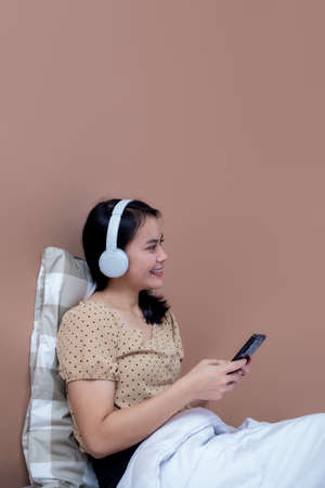 Woman sitting on chair with laptop at table holding drinking glass and looking at screenの写真素材