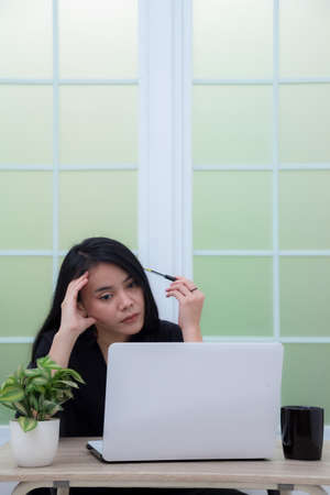Business woman sitting on chair with laptop on table while holding drinking glass and smilingの写真素材