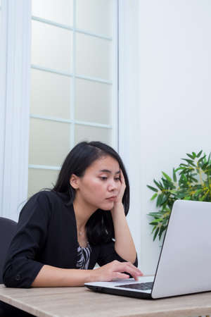 Business woman sitting on chair with laptop on table while holding drinking glass and smilingの写真素材