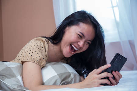 Business woman sitting on chair with laptop on table while holding drinking glass and smilingの写真素材