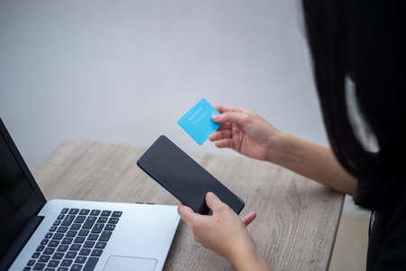 Business woman sitting on chair with laptop on table while holding drinking glass and smilingの写真素材