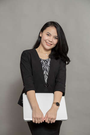 Happy business woman holding and looking at laptop screenの写真素材