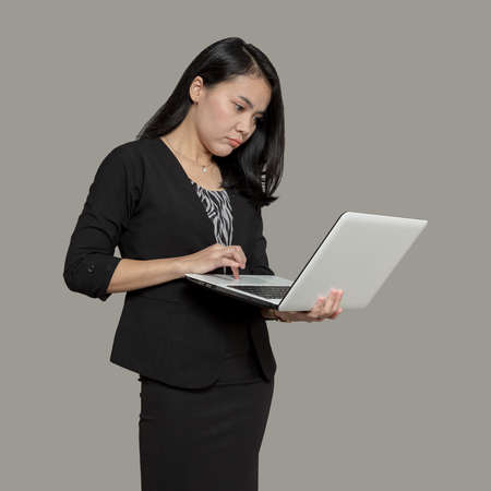 Happy business woman holding and looking at laptop screenの写真素材