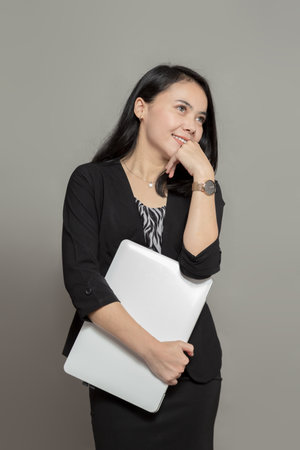 Indonesian woman wearing suit posing with holding laptopの写真素材