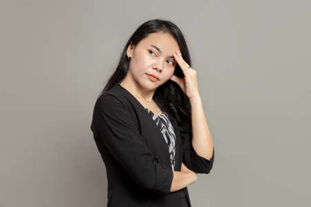 Business woman is imagining with pen on cheek while holding clipboardの写真素材