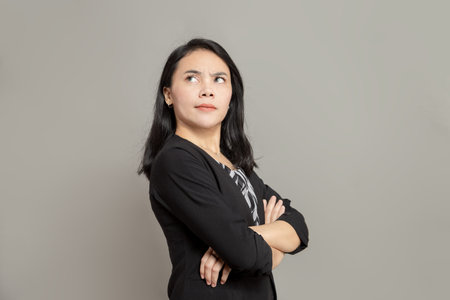 Business woman is imagining with pen on cheek while holding clipboardの写真素材