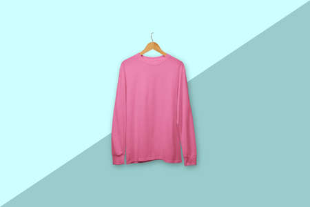 Pink long sleeve t-shirt on wooden hanger isolated on backgroundの写真素材