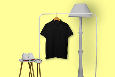 Black polo shirt with wooden hanger hanging on rack display isolated on plain backgroundの写真素材