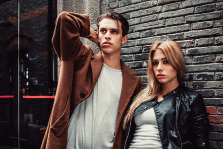 Young and trendy man and woman posing of the street with brick walls. Fashion styleの写真素材