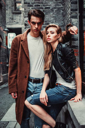 Young and trendy man and woman posing of the street with brick walls. Fashion styleの写真素材