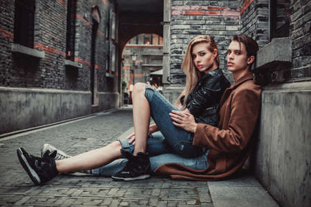 Young and trendy man and woman posing of the street with brick walls. Fashion styleの写真素材