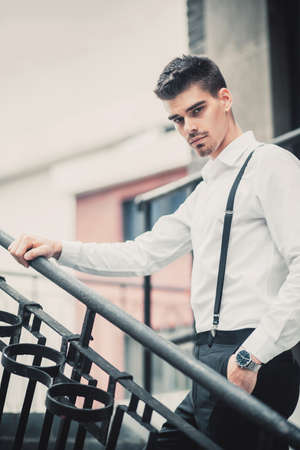 Young stylish man model in classic clothes posing near stairs. Fashion shotsの写真素材