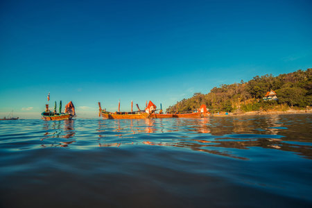 Longtale boat at the Thai beach. Paradise sand beach place. Boats on the clear water and blue sunrise sky.の写真素材