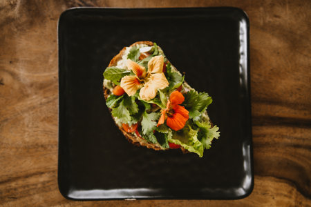 Close up shot of avocado bruschetta with tomatoes and herbs. Morning tropical breakfast toast on black plateの写真素材