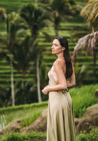 Stylish lady in green sexy dress on footpath rice terrace. Young elegant lady admiring evergreen balinese natureの写真素材