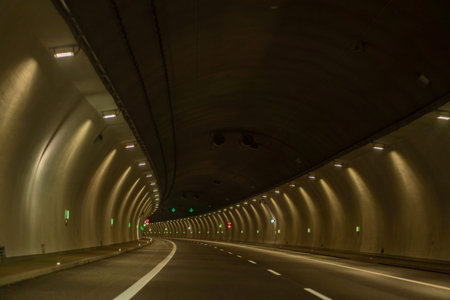 Underground city road tunnel, curve night illuminated freeway with carの写真素材