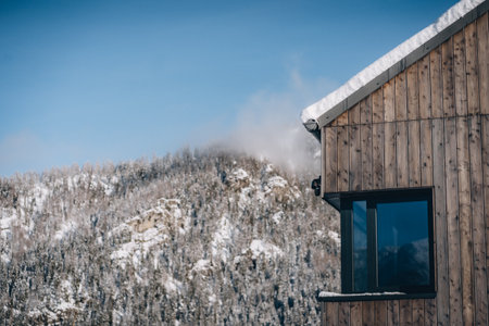 Modern wooden cabin with window and snowdrift on roof, house in Low Tatras, Slovakiaの写真素材