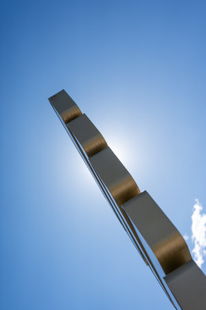 Close-up of an abstract metal sculpture, viewed against a clear blue sky. The minimalist design and perspective create a striking and modern visual.の写真素材