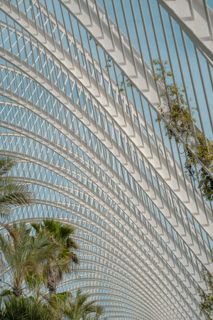Close-up of a modern metal lattice structure with plants growing through the gaps. The design...