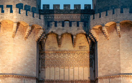 Close-up of the Serranos Towers in Valencia, Spain, illuminated at night. The detailed architectural features and lighting create a historic and majestic atmosphere.の写真素材