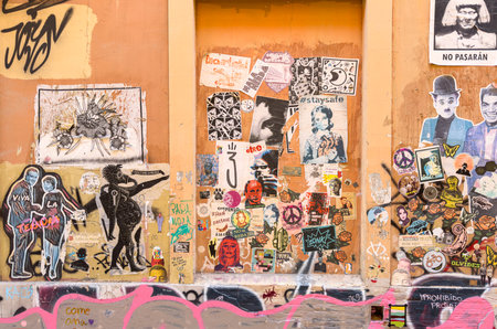 Colorful urban wall covered with various stickers, posters, and street art, showcasing diverse artistic expressions and vibrant city culture.の写真素材