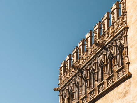 Close-up view of the Llotja de la Seda ornate Gothic architecture in Valencia, Spain, featuring intricate carvings and decorative elements against a clear blue sky.の写真素材