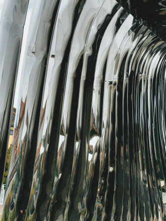 Detailed view of a reflective metal sculpture in a park, highlighting the interaction between nature and contemporary art through distorted reflections.の写真素材