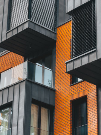 Contemporary building facade featuring a combination of red brick and black metal elements, highlighting modern architectural design and urban development.の写真素材