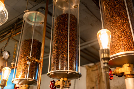 Vertical cylindrical containers filled with roasted coffee beans in a caf setting. Industrial coffee preparation equipment.の写真素材