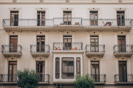 A charming vintage style building facade that features elegant balconies and lush urban greenery in the cityscape in Tarragona, Spainの写真素材